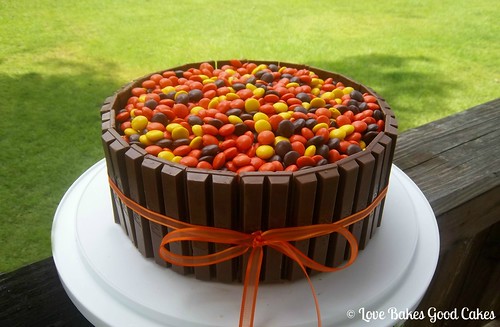 Kit-Kat Cake with Reeses Pieces on top on cake stand.