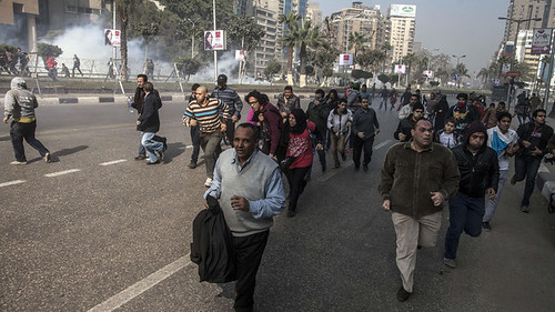 Egyptian anti-government protesters run for cover from tear gas during clashes with police in the capital Cairo on January 25, 2014 following a rally marking the anniversary of the 2011 uprising. by Pan-African News Wire File Photos