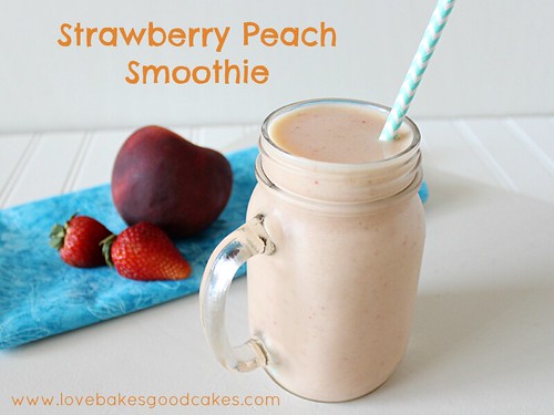 Strawberry Peach Smoothie in glass with straw and fresh fruit close up.