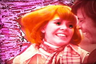 A still from Dinorah's film, with an orange and pink model whose eyes are whited out