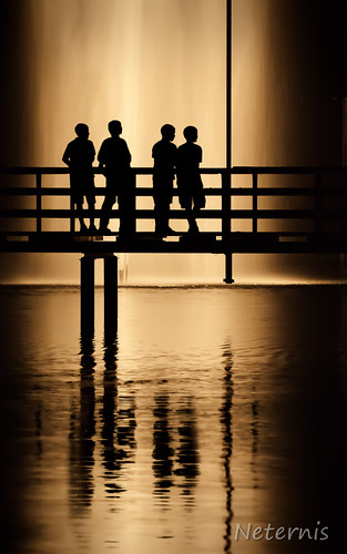 boy sea people orange lake black color reflection boys water fountain silhouette yellow night standing dark person mirror stand still dock bright jetty gang silhouettes rail figure railing outline outlines balustrade