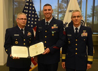 Master Chief Petty Officer of the Coast Guard Steven Cantrell and Vice Adm. Peter Neffenger, vice commandant of the Coast Guard, present Petty Officer 1st Class Travis Cutler with a Coast Guard Commendation Medal in recognition of his selection as the Coast Guard's 2013 Enlisted Person of the Year during a ceremony at Coast Guard Headquarters in Washington, D.C., June 6, 2014. Cutler, an avionics electrical technician currently assigned to Coast Guard Air Station Houston, was then meritoriously advanced to the rate of chief petty officer. U.S. Coast Guard photo by Telfair Brown
