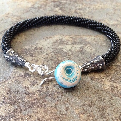 Kumihimo bracelet with ceramic button by Lesley Watt, and handcrafted sterling silver hook clasp. #com #aje #artjewelry #handmadeartisanjewelry