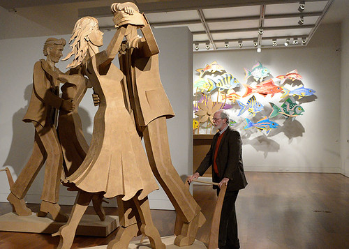 man standing in museum looking at cardboard art that features dancing figures