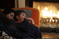 mother and son resting on the couch by the fire 