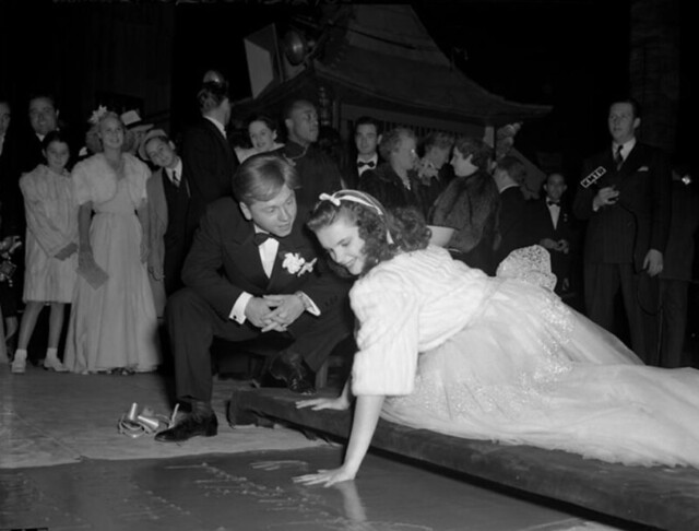 Mickey Rooney watching Judy Garland put handprint in cement at Grauman's Theatre during Babes in Arms film premiere at the chinese theater 1939