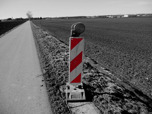 Warning - roadworks sign in black and white with red color cut out (partial de-saturation)