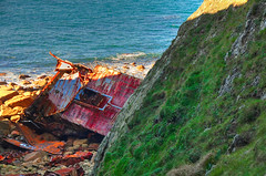 Shipwreck on rocky beach between cliffs