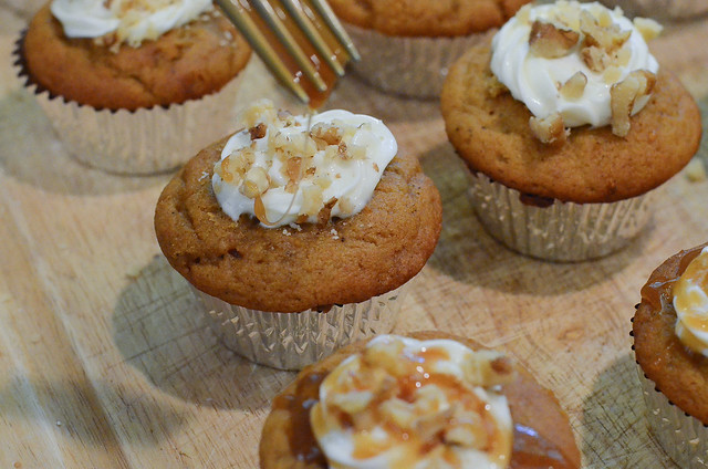 A fork drizzles caramel on top of the cupcakes.