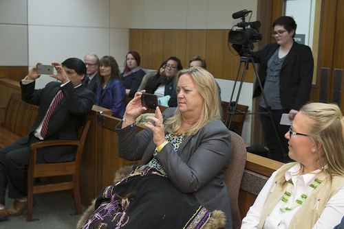 Executive Council member Diana Zirul, at center, photographs the signing ceremony Thursday at about 3 p.m. in Fairbanks.