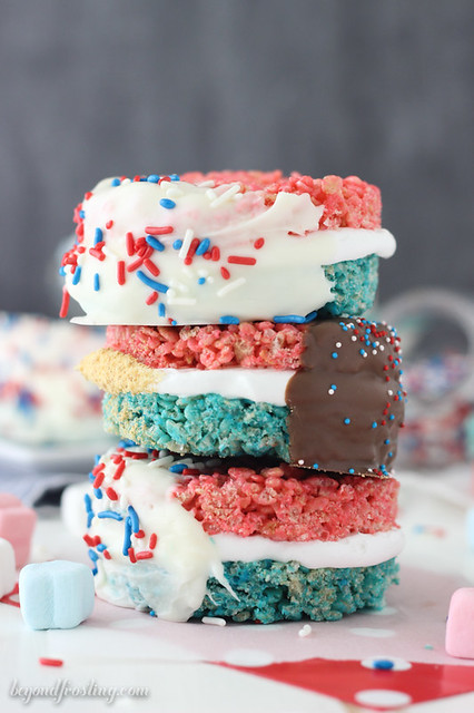 Celebrate with these Patriotic Rice Krispie Treat S'mores. Red and blue Rice Krispie Treats smothered in marshmallow frosting and dipped in chocolate. Finish it off by rolling them in graham crackers. 