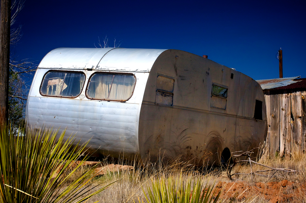 Rustic abandoned broken down trailer in the southwest with a bright blue sky, photography art, for home and office décor