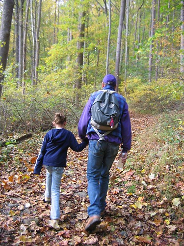 Father and daughter holding hands on a hike in the woods 