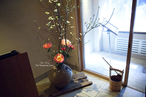 Vase filled with tall floral centerpiece and a wooden bucket near the entry