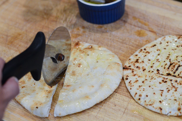 The oiled Pita is cut in half with a pizza cutter.