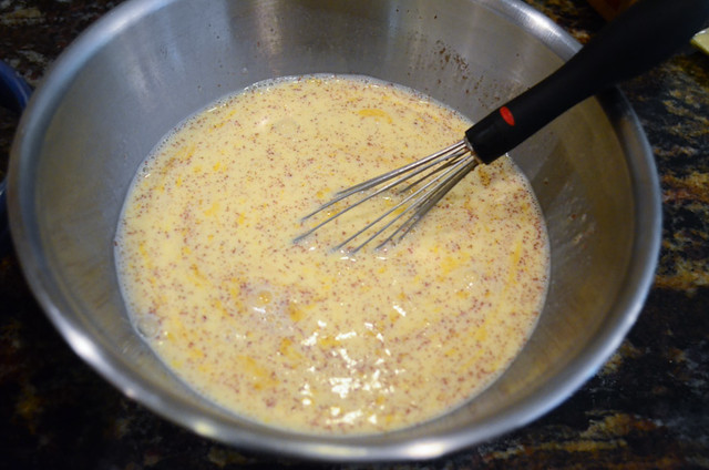 An egg and spice mixture is whisked together in a metal mixing bowl.