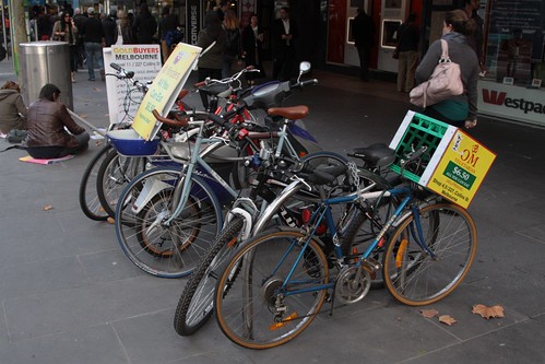 'OM Vegetarian' advertisement tied to a parked bike on Swanston Street