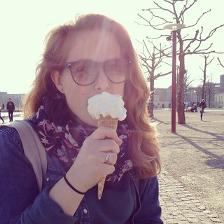 A woman eats an ice cream cone on a winter day