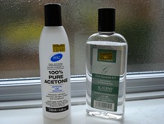 Two bottles standing on a white bathroom windowsill with a frosted-glass window behind them.  The left-hand bottle is labelled “100% Pure Acetone” and has a price tag on it for £2.69.  The right-hand bottle is labelled “Pure Glycerine BP” and has a price tag for £2.29.