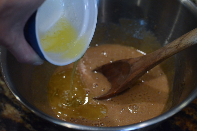 Melted butter is added to other ingredients in a mixing bowl.