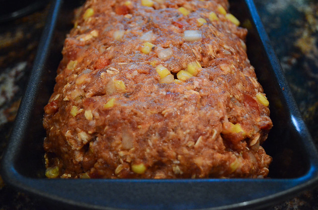 A close up of raw meatloaf in a loaf pan.