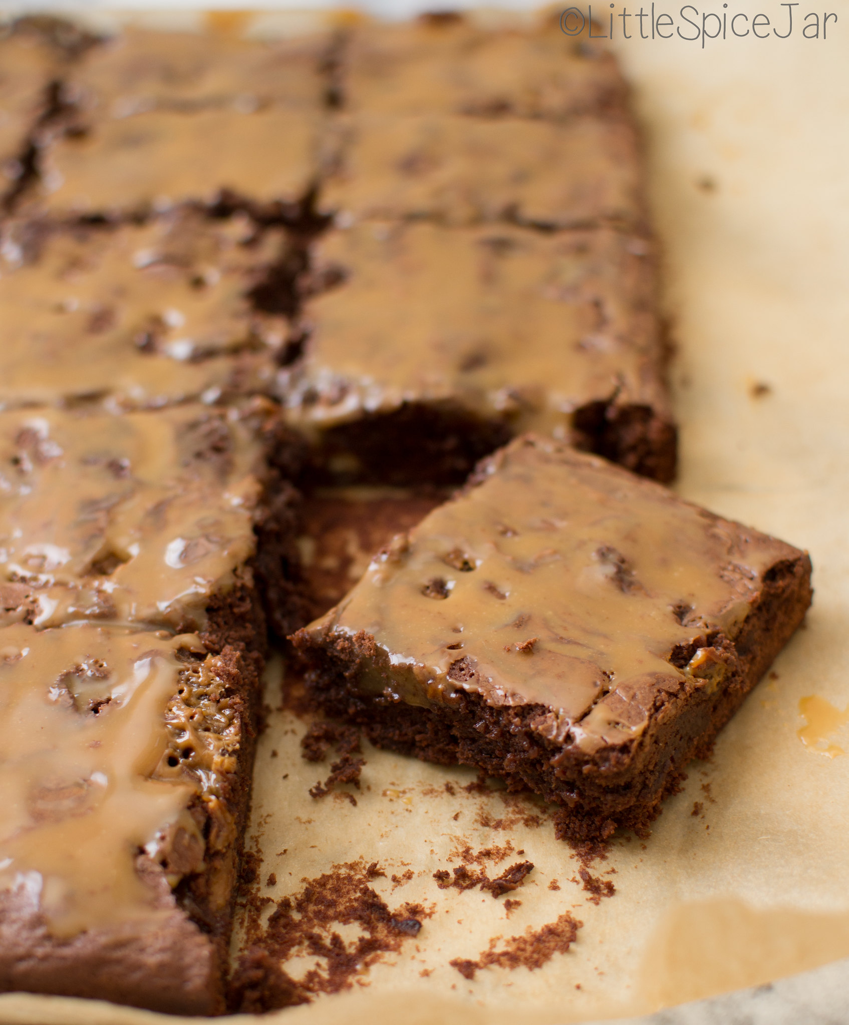 squares of prepared brownies with caramel drizzle on parchment paper 