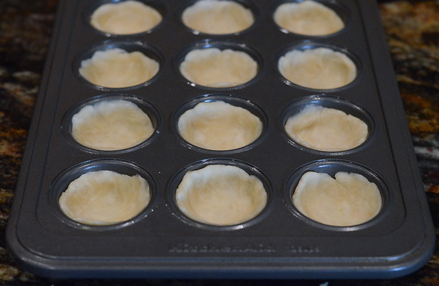 A mini muffin pan with dough pressed into it.