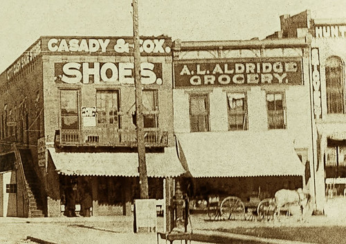 horses people usa signs man men history sepia fence buildings advertising awning hardware clothing shoes indiana streetscene transportation drugs shops pedestrians storefronts grocery banks businesses wagons barbers dentists jeweler rushville realphoto rushcounty hoosierrecollections