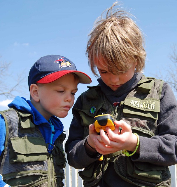 Children study a GPS unit while geocaching