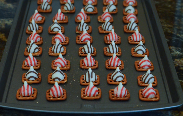 Pretzels topped with Candy Cane Hershey's Kisses on a baking sheet.