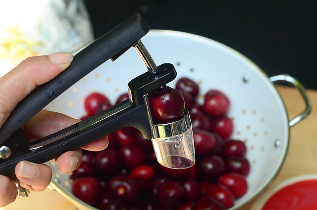 A cherry pitting tool being used to remove a pit from a cherry.