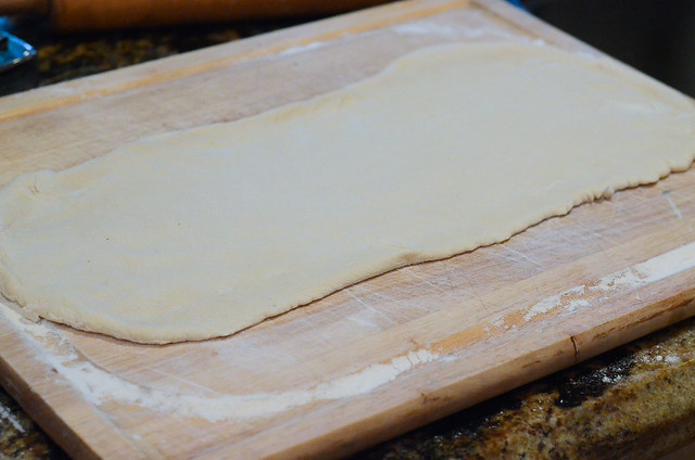 Bread dough rolled into a rectangle on a wood board.
