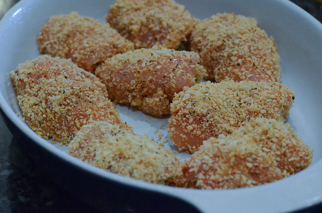The stuffed and breaded chicken in a baking dish.