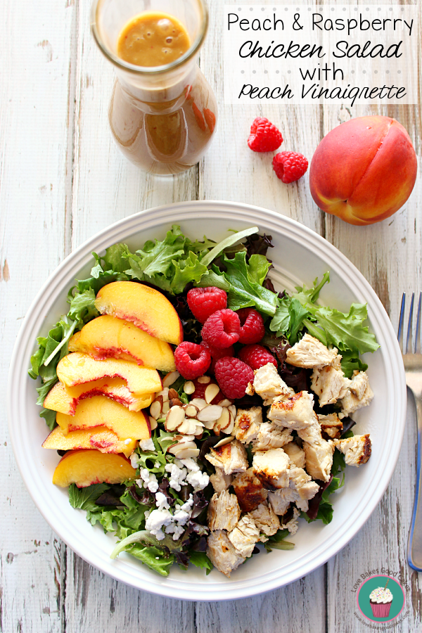 Peach & Raspberry Chicken Salad in a white bowl with fresh fruit and a fork.