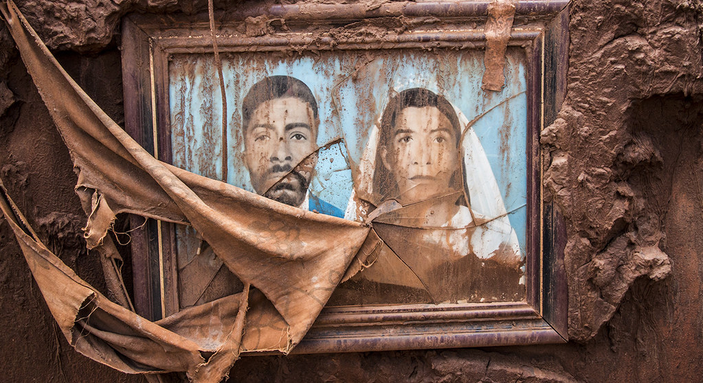Foto pintada de casal com vidro despedaçado encrustada na lama