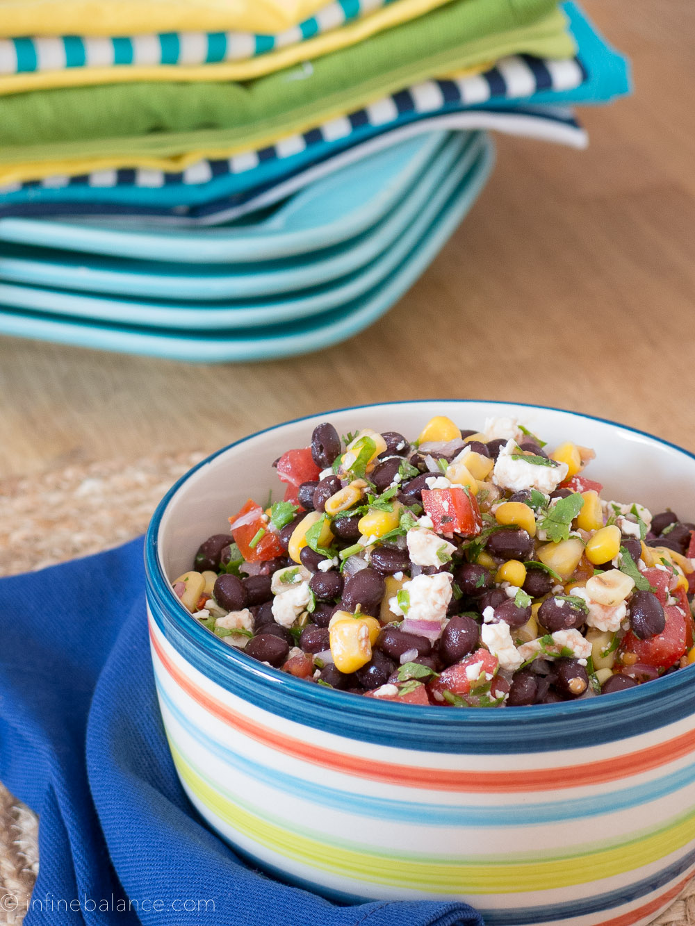 black bean and corn salsa with feta and tomatoes in a blue triped bowl