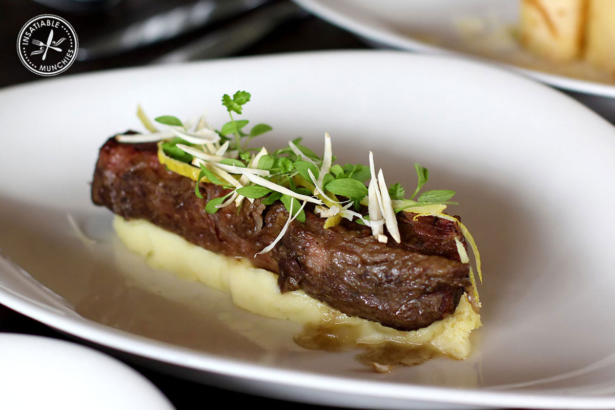 Tender braised beef short ribs are slow cooked, removed from the bone, and served on a bed of creamy mash.
