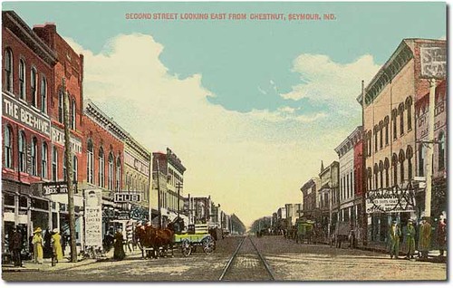 horses people woman usa signs man color men history buildings walking advertising awning hardware clothing women shoes indiana streetscene transportation shops pedestrians seymour interurban businesses wagons jacksoncounty hoosierrecollections
