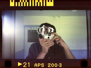 Reflected self-portrait with Canon Ixus M-1 camera and crown glasses