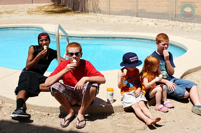 Kids sitting near pool eating ice cream cones with a bottle of Wet Nap Hand Wipes nearby.