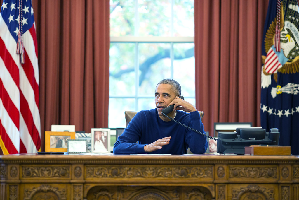 <p>President Barack Obama makes Thanksgiving Day phone calls from the Oval Office to U.S. troops stationed around the world, Nov. 24, 2016. The President's Coast Guard military aide, LCDR Ginny Nadolny is at right.<br />
(Official White House Photo by Pete Souza)<br />
<br />
This official White House photograph is being made available only for publication by news organizations and/or for personal use printing by the subject(s) of the photograph. The photograph may not be manipulated in any way and may not be used in commercial or political materials, advertisements, emails, products, promotions that in any way suggests approval or endorsement of the President, the First Family, or the White House.</p>