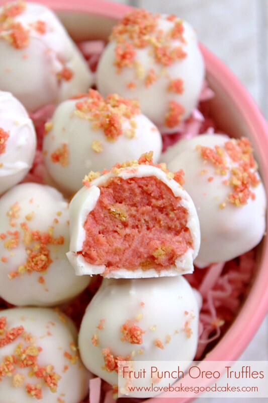 Fruit Punch Oreo Truffles in a bowl with a bite taken out showing the inside.