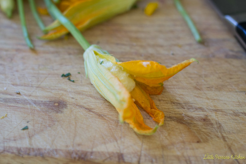 Gently open up the squash blossom and remove the small stem from inside the flower, being careful not to tear the delicate petals. Leave the large stem intact, this will help when dipping the stuffed flower into the batter.