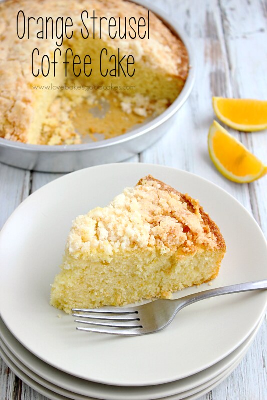 Orange Streusel Coffee Cake on a stack of plates with a fork and orange slices.