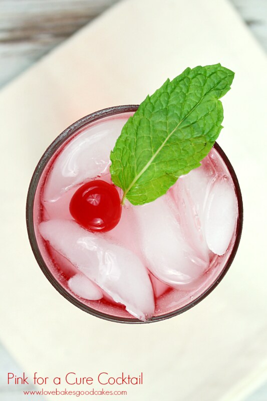 Pink for a Cure Cocktail in a glass with a mint leaf and a cherry on the top.