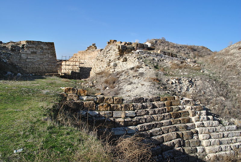View of the Gordion Citadel Mound and previously excavated fortifications. Note the scaffolding at the Citadel Gateway in the background, a visible reminder of the ongoing architectural conservation and restoration work at the site. Vikicizer, Wikimedia Commons