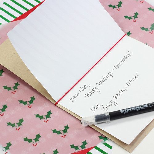 holiday card with note written inside displayed with pen and decorative papers