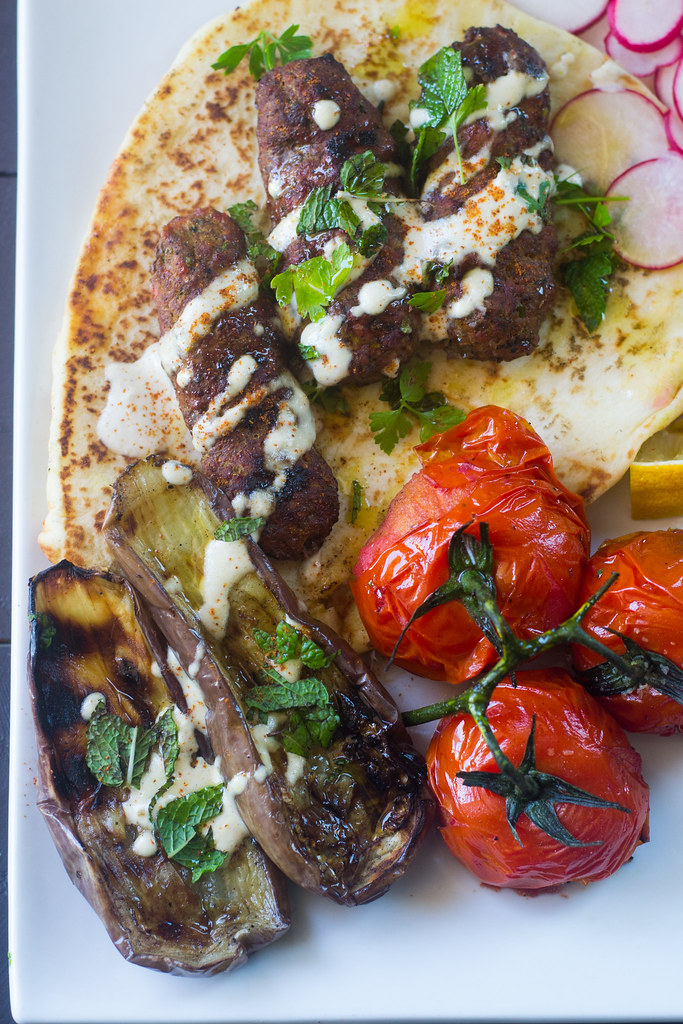 Middle Eastern grill with grilled kofta, eggplant and tomatoes all drizzled with garlicky tahini sauce.