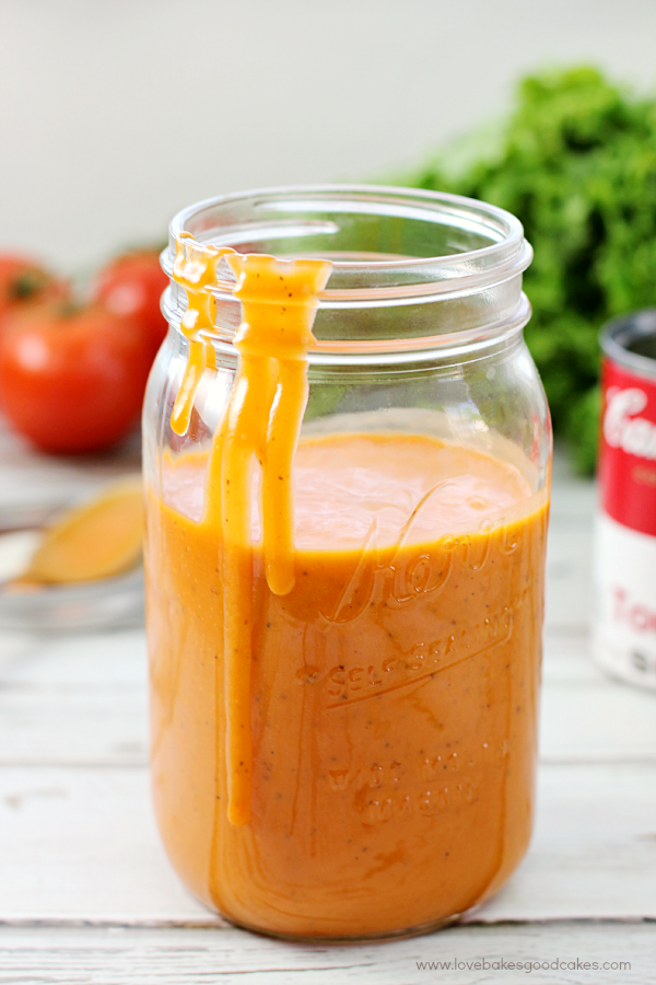 Tomato Soup Salad Dressing in a glass jar with dressing running down the side of the jar.