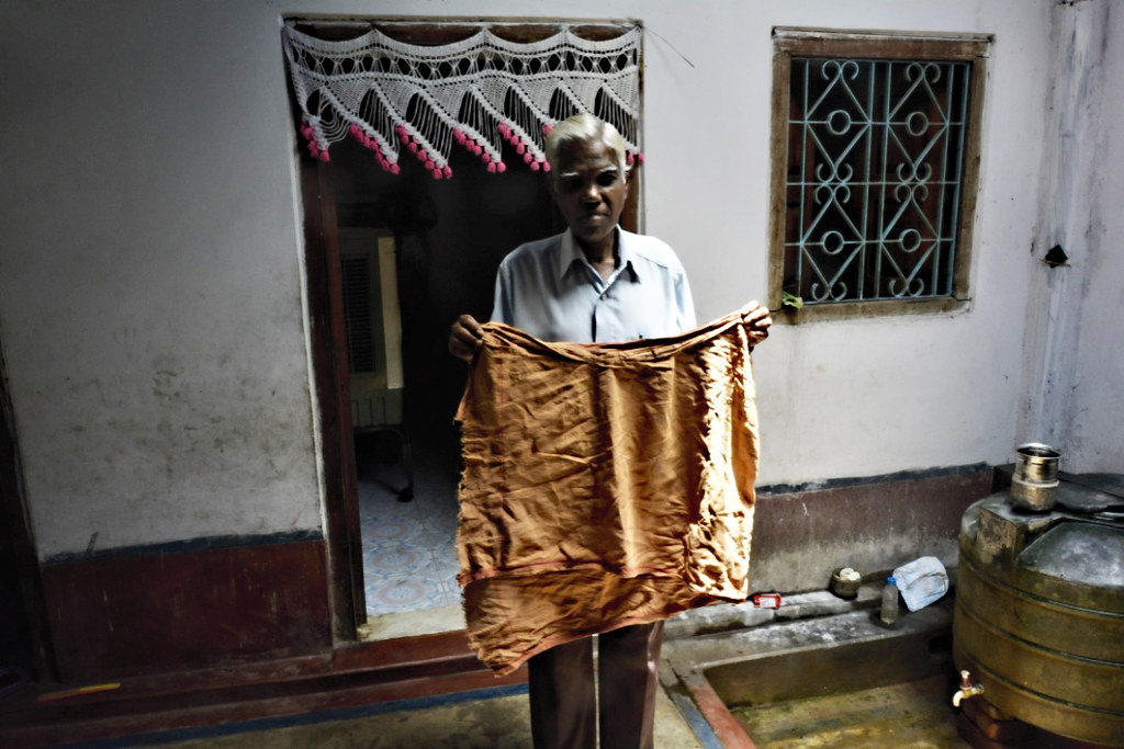 Yogeshwar Patra, a resident of Talabeda, shows an originally white cloth turned reddish after being used to filter water.